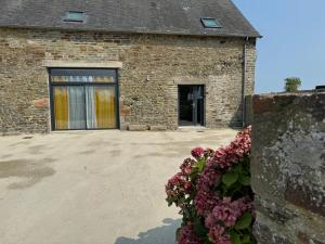 a brick building with a window and flowers at Gîte au pied du Mont Saint Michel in Pontorson