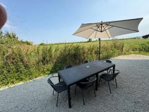 a black table with chairs and an umbrella at Gîte au pied du Mont Saint Michel in Pontorson +3 photos