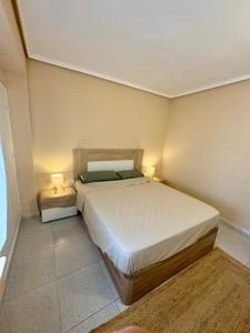 a bedroom with a bed and two lamps on two tables at 1st Line Beach Direct Access Private Parking in Valencia