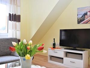 a living room with a television and a vase with flowers at Ruhiges Ferienhaus in Floh-Seligenthal in Seligenthal