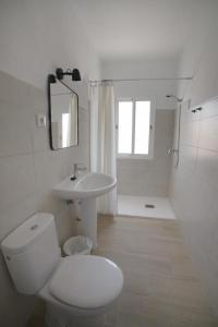 a white bathroom with a toilet and a sink at Gran alojamiento a 1 metro de la playa con magnificas vistas in Chipiona