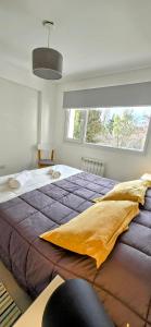 Una cama grande en un dormitorio con una ventana grande. en Departamento céntrico Pioneros y Campichuelo, en San Carlos de Bariloche