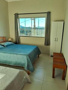 サン・ロウレンソにあるApto Vista das Montanhasのベッドと大きな窓のある寝室