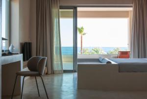 a bedroom with a bed and a chair and a window at Alykes Villa - Seaview escape in Plakias +61 photos