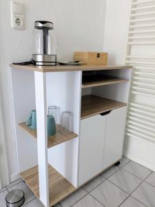 a kitchen with a white stand with wooden shelves at Zimmer mit eigenem Bad und eigenem Eingang in Bad Oeynhausen
