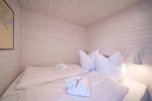 a white room with two towels on a bed at Hausboot Schatzkiste in Fehmarn