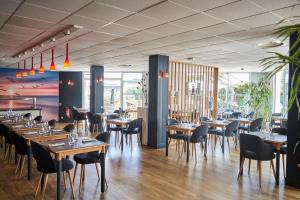 a dining room with wooden tables and chairs at Thalacap Île de Ré - Thalasso & Spa in Ars-en-Ré