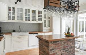 a kitchen with white cabinets and a brick wall at Beautiful Home In Torekov in Torekov