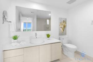 a white bathroom with a sink and a toilet at Balcony with Infinite Views - Poolside Comfort in Hallandale Beach