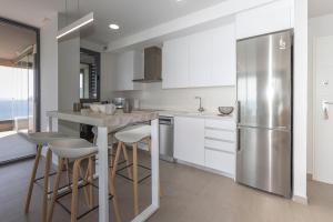 a kitchen with white cabinets and a stainless steel refrigerator at Apartamento Infinium 4 - Costa CarpeDiem in Calpe