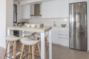 a kitchen with white cabinets and a island with bar stools at Apartamento Infinium 4 - Costa CarpeDiem in Calpe