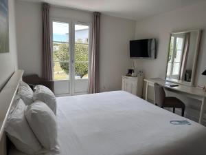 a white bedroom with a bed and a desk and a window at Thalacap Île de Ré - Thalasso & Spa in Ars-en-Ré +35 photos