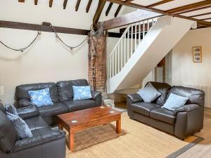 - un salon avec des canapés en cuir et une table dans l'établissement Trailor Cottage, à Weybourne