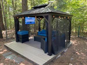 a gazebo with blue chairs in the woods at Serene Forest Lodge I Adventure Meets Serenity in Madison