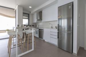 a kitchen with a stainless steel refrigerator and bar stools at Apartamento Infinium 4 - Costa CarpeDiem in Calpe