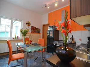 a kitchen with orange walls and a table with a vase of flowers at Charming Forest Escape for Two in Langewiesen
