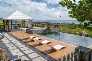 a swimming pool with two chairs and a gazebo at Residence Foulsafat in Rodrigues Island