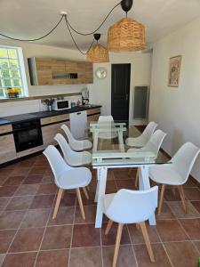 a kitchen with a glass table and white chairs at Chez Monique - Mur de Sologne - 8 personnes in Mur-de-Sologne