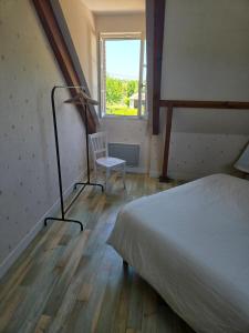 a bedroom with a bed and a chair and a window at Chez Monique - Mur de Sologne - 8 personnes in Mur-de-Sologne