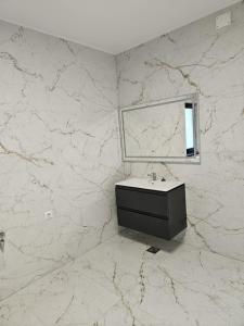 ein Badezimmer mit einem Waschbecken und einem Spiegel an einer Marmorwand in der Unterkunft Vila veverita in Schitu-Tarcău