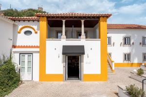 Un edificio blanco y amarillo con una puerta. en &Tales Hotel - Óbidos, en Óbidos