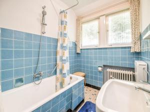 a blue tiled bathroom with a tub and a sink at Geräumiges Apartment am Waldrand im Sauerland in Medebach +32 photos