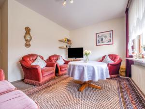 a living room with red chairs and a table at Geräumiges Apartment am Waldrand im Sauerland in Medebach