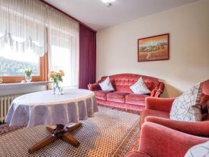 a living room with a red couch and a table at Geräumiges Apartment am Waldrand im Sauerland in Medebach