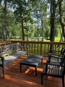 two benches sitting on a wooden deck with trees at Holiday House Nature in Lier