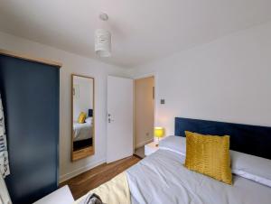 a bedroom with a bed with yellow pillows and a mirror at Cottage by historical dockyard in Portsmouth