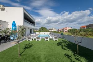 einen Garten mit Stühlen und einem Pool in der Unterkunft Villa Zlatne NiTi with heated pool in Kaštela