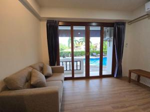a living room with a couch and a sliding glass door at Natural Samui Hotel in Bophut