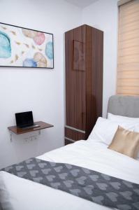 Un dormitorio con una cama y una computadora portátil en un escritorio. en Blacky's, en Lekki
