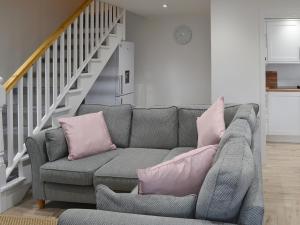 a living room with a gray couch with pink pillows at Spring Tides in Beadnell +10 photos