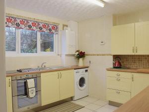 a kitchen with white cabinets and a washing machine at Ty Capel Seion in Cardigan