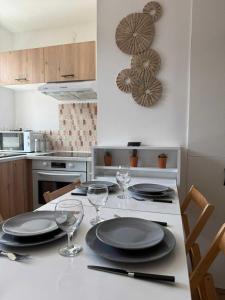 a kitchen with a table with plates and wine glasses at Ambiance Bohème, Confort Cosy in Calais +12 photos