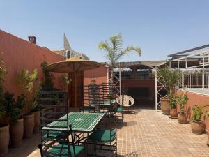 a patio with tables and chairs and an umbrella at Riad DIHYA & Rooftop Pool in Marrakesh