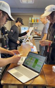 a group of people standing around a table with a laptop at IntentsGP @ Spa-Francorchamps F1 in Francorchamps