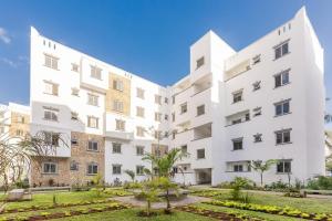 a large white building with a garden in front at 3bdrm Mombasa CBD Aircon gym, washer ,free pool in Mombasa
