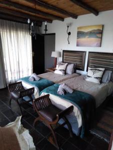 a bedroom with two beds and two chairs at Mafuta Lodge - Mabalingwe Nature Reserve in Warmbaths