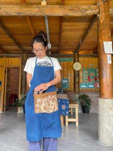 eine Frau in einer blauen Schürze hält eine Handtasche in der Unterkunft The Zen Garden Sapa in Sa Pa