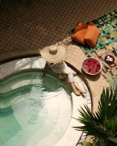 una donna seduta su un tavolo accanto alla piscina di Marrakech Riads, Angsana Heritage Collection a Marrakech