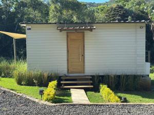 a small white shed with a wooden door and stairs at Eco Lodge Chamarel in Chamarel