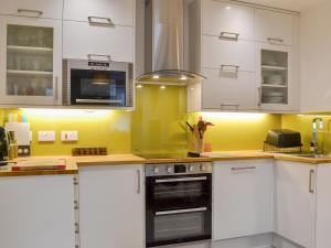 a kitchen with white cabinets and a yellow wall at Retro Retreat in Filey