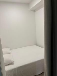 ein Bett in einem Zimmer mit weißen Wänden und weißen Laken in der Unterkunft Appartement T2 chambre plus cabine, terrasse vue piscine in Bormes-les-Mimosas + 16 Fotos