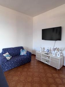 a living room with a blue couch and a tv at Villino Maria Elena in Valderice