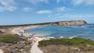 a beach with a bunch of people with umbrellas at Sa Domo de Lillo e Arturo in Bonarcado