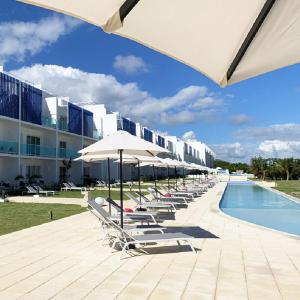a row of lounge chairs and umbrellas next to a pool at Exclusive Punta Cana Apartment - Private Jacuzzi in Punta Cana