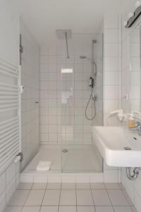 a white bathroom with a shower and a sink at Mooeve Friedrichs Mid in Berlin