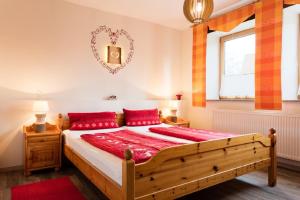 Am Rückerlhof في فالدمونشن: غرفة نوم مع سرير خشبي كبير مع وسائد حمراء